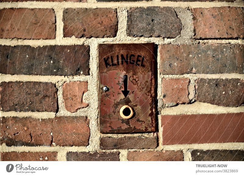 Backstein- oder Ziegelmauer eines Denkmal geschützten Funktionsbaus mit eingebauter Klingel auf rostiger Eisenplatte in die das Wort Klingel und ein Pfeil zum Klingelknopf eingeschnitten ist.