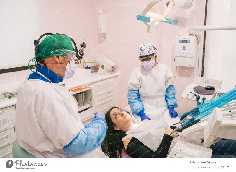 Unerkennbarer Zahnarzt und Krankenschwester interagieren mit Patientin in Klinik Krankenpfleger geduldig Gerät medizinisch Stomatologie professionell Uniform