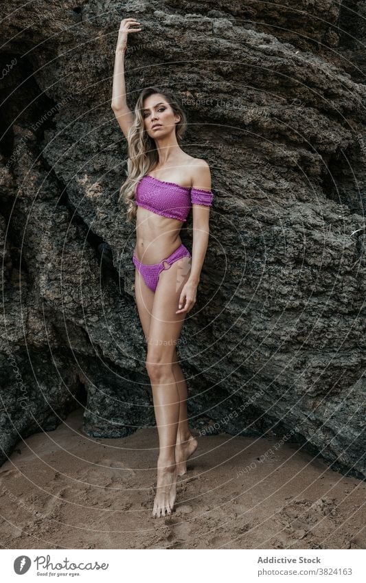 Schlanke Frau in Bademode in der Nähe von Felsen am Ufer Bikini Seeküste Sommer Feiertag Anmut schlank charmant Stein Badebekleidung Natur Strand Körper
