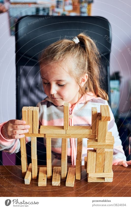 Kleines Mädchen im Vorschulalter spielt mit Holzklötzen Spielzeug, das ein Haus baut Aktivität Klotz Blöcke Baustein bauen Kind Kindheit Konzept Konstruktion