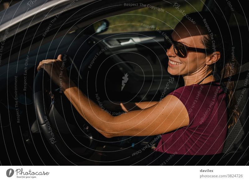 Frau in ihrem Auto hält das Lenkrad und lächelt. Laufwerk sorgenfrei Lachen Glück Lächeln Freude heiter junger Erwachsener Anschluss Autoreise echte Menschen