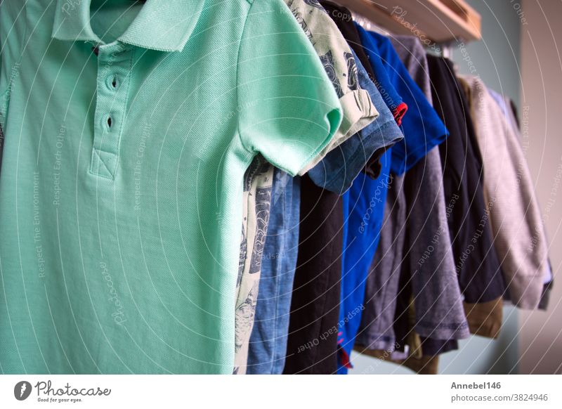 Jungen ziehen Kleider an, die in einem Metallregal hängen, Kinderzimmer der Jungen Lagerung im Zimmer Mode Ablage Bekleidung Kleidung anhaben Kleiderschrank