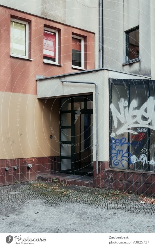 Hauseingang, Fenster und Graffiti in der Stadt Eingang Wohnhaus Eingangstür Großstadt trist Tristesse Realität Fassade Gebäude Tür Mauer Bauwerk Wand