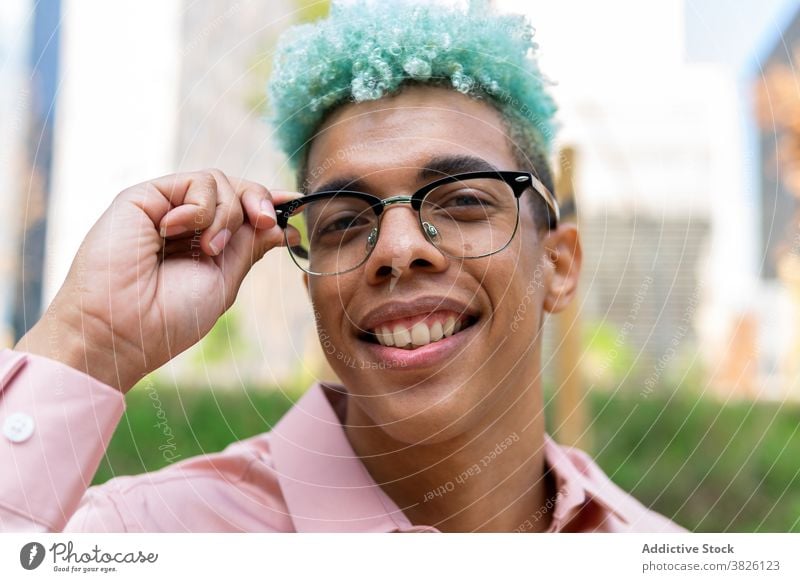 Lächelnde ethnischen Mann mit Afro-Frisur und in Gläser in der Stadt blaue Haare Afro-Look gutaussehend Stil Vorschein Brille trendy Generation männlich schwarz