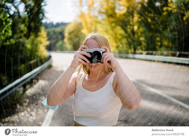 Frau mit Fotokamera steht auf der Straße im Herbst Landschaft fotografieren Fotoapparat Wald Fotografie Natur Fahrbahn Reise reisen fallen Abenteuer Hobby