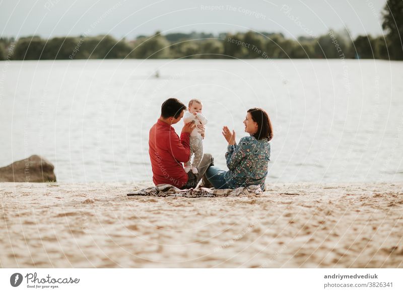 glückliche Familie, die sich am See ausruht. Familie mit einem kleinen Kind Natur Glück aussruhen Eltern Mutter Tochter Sommer Liebe Zusammensein Feiertag