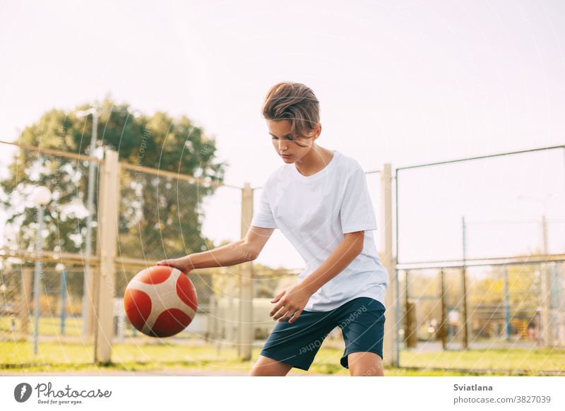 Ein fokussierter, süßer Athlet führt den Ball in einem Basketballspiel an. Ein Junge spielt nach der Schule Basketball. Sport, gesunde Lebensweise, Freizeit