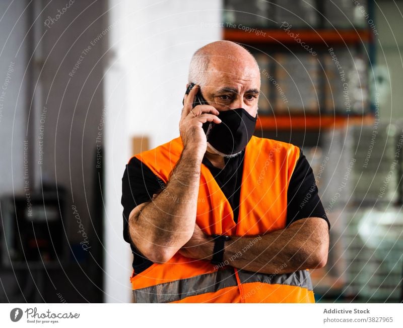 Konzentrierte männliche Lagerarbeiter sprechen auf Smartphone Mann Arbeiter Gespräch Telefonanruf ernst Manager reden Lagerhalle bei der Arbeit Arbeitsplatz