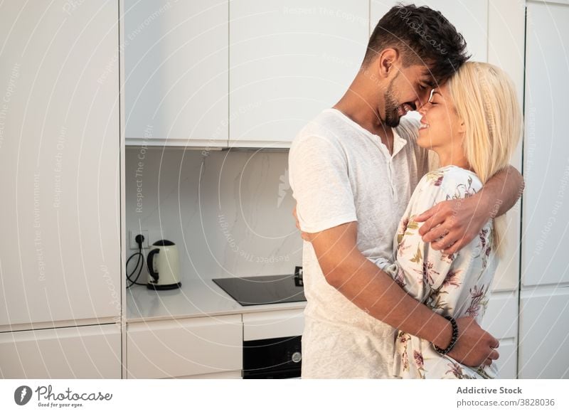 Fröhliches Paar umarmt zärtlich in der Küche Umarmung Umarmen Berührungsnase Liebe Zusammensein Morgen heimwärts heimisch Freundin modern Partnerschaft