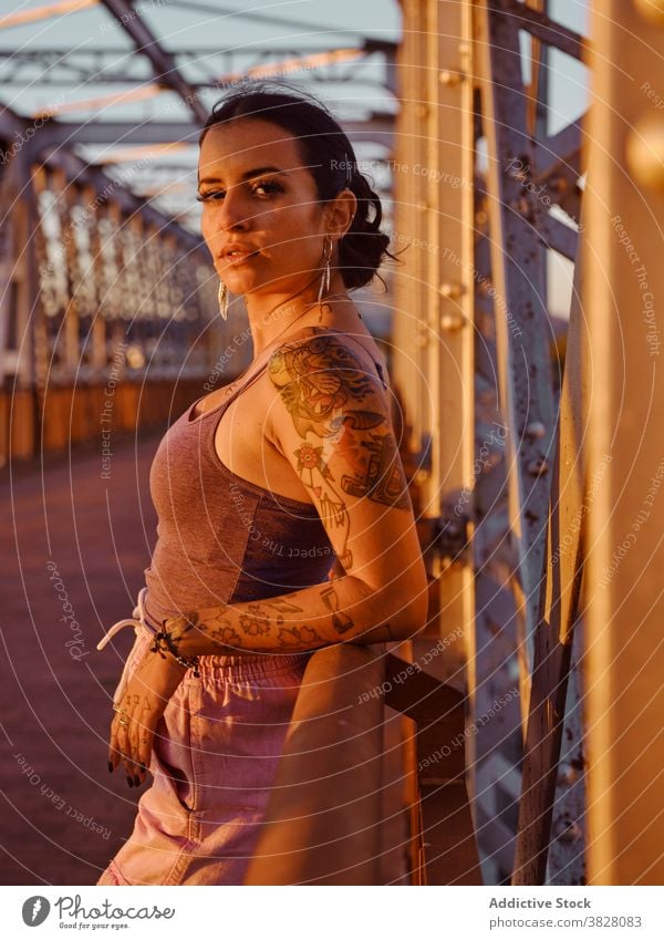 Stilvolle Frau in Tattoos stehen in der Stadt trendy Brücke Metall Sonnenuntergang Sommer sich[Akk] entspannen ruhen genießen jung urban Freiheit Freude froh