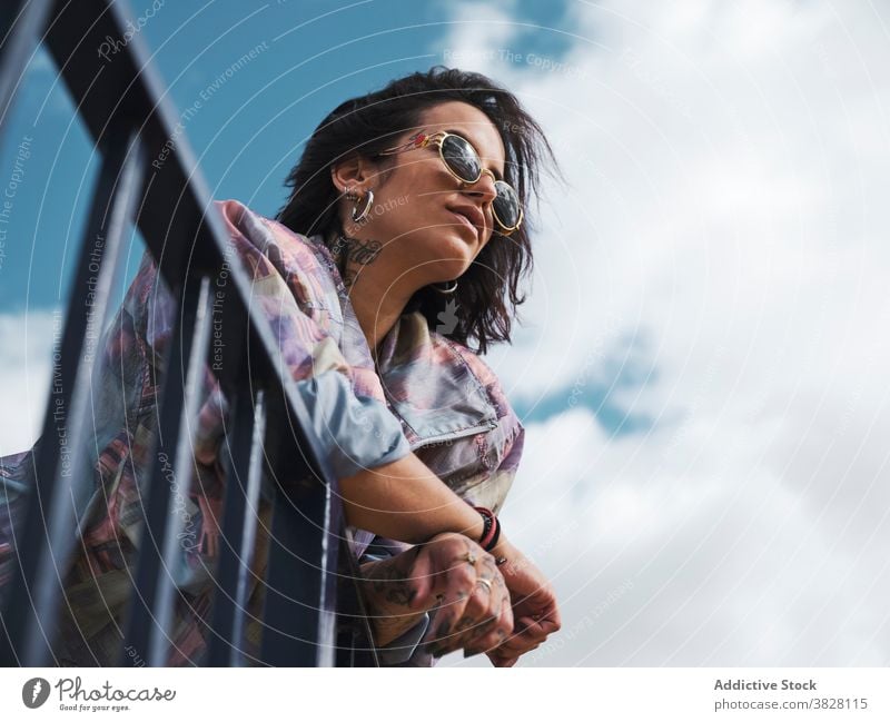 Stilvolle Frau in Tattoos stehen in der Stadt Streetstyle tausendjährig Bestimmen Sie Sonnenbrille Accessoire jung unabhängig Metall Zaun Straße Mode
