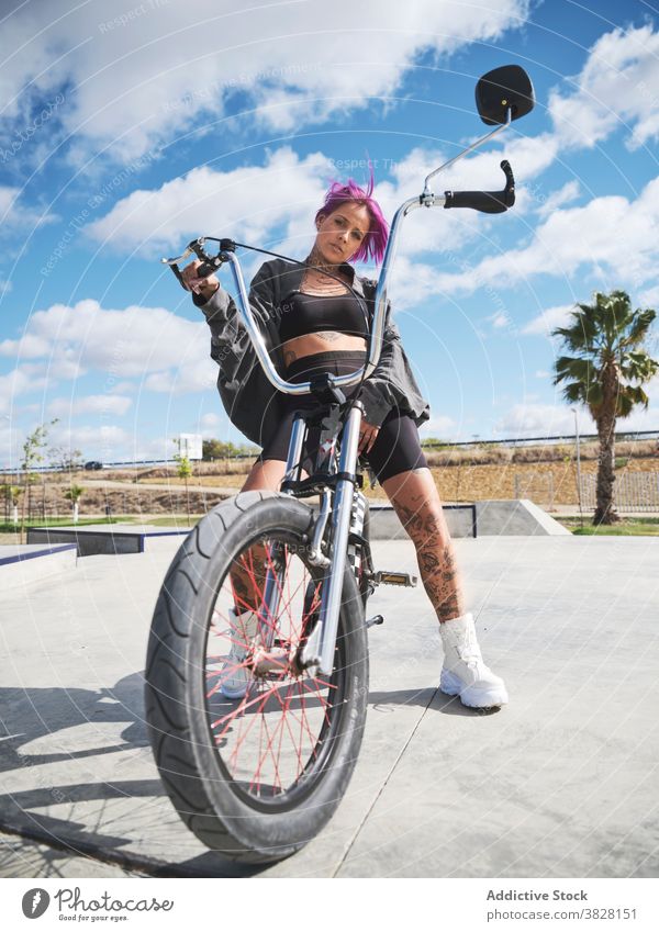 Ernste Frau auf dem Fahrrad im Skatepark bmx selbstbewusst Skateplatz extrem ernst Tattoo Stil Outfit sitzen trendy urban jung cool Verkehr Freiheit Sommer