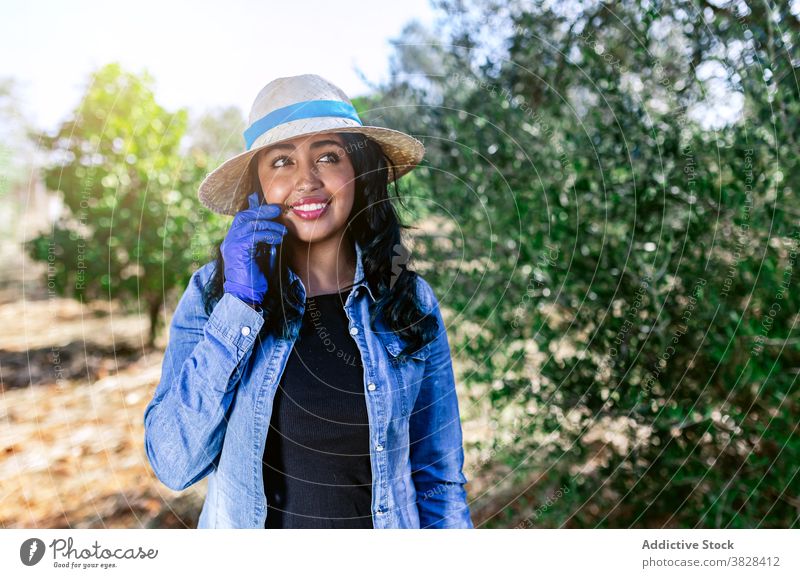 Junge Frau spricht am Telefon, während sie im Garten steht sprechend benutzend positiv Arbeit Obstgarten Ernte Frucht Bauernhof Anschluss Mitteilung digital