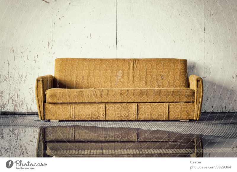Ausrangiertes altes braunes Sofa gegen schmutzige Wand Liege Möbel abgeworfen ruiniert dreckig verwendet gelb Straße im Freien Müll Trödel gebrochen Wasser