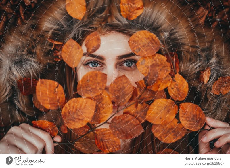 Frau hält Herbstblätter als natürliche Gesichtsmaske Herbstfarben Herbstlaub Herbst-Vibes Hintergrund schön schöne Frau Kaukasier Feier Sauberkeit abschließen
