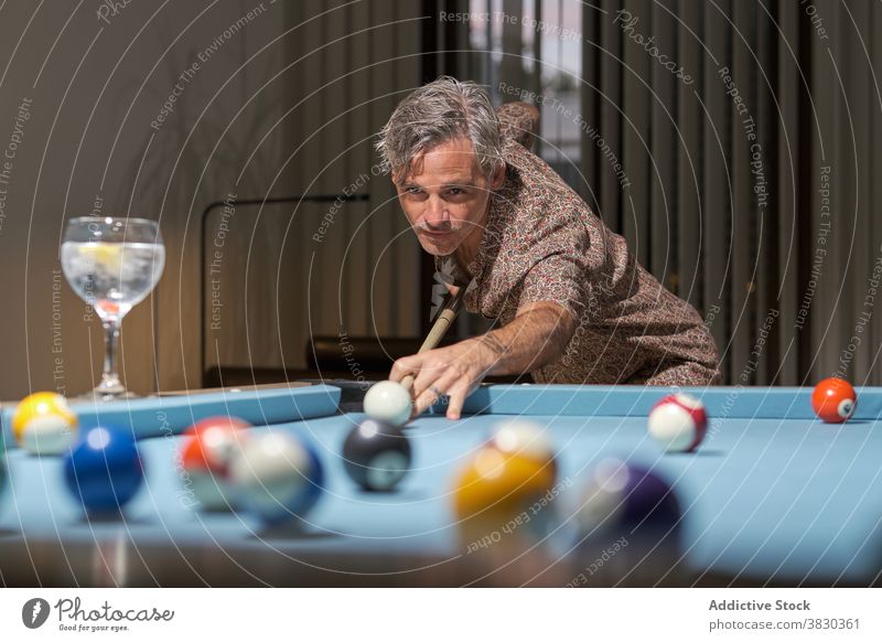 Konzentrierter Spieler, der beim Billardspielen die Kugel mit dem Queue stößt Mann Freizeit Hobby Konzentration Aktivität selbstbewusst ernst männlich