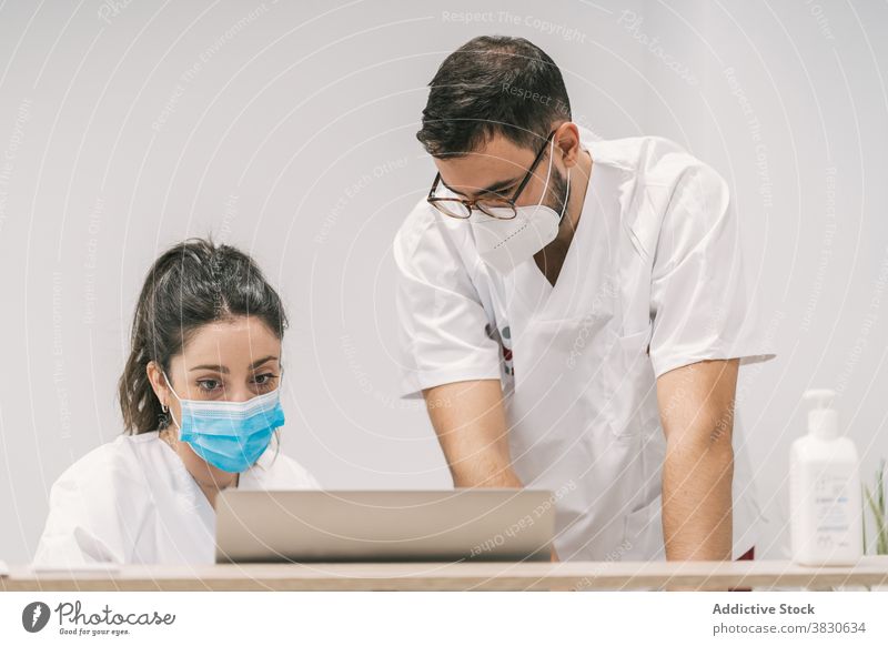 Beschäftigte Ärzte arbeiten am Laptop im Krankenhaus Klinik Arzt Zusammensein Kollege Mundschutz Arbeit professionell Job Beruf Netbook Gerät Gesundheitswesen