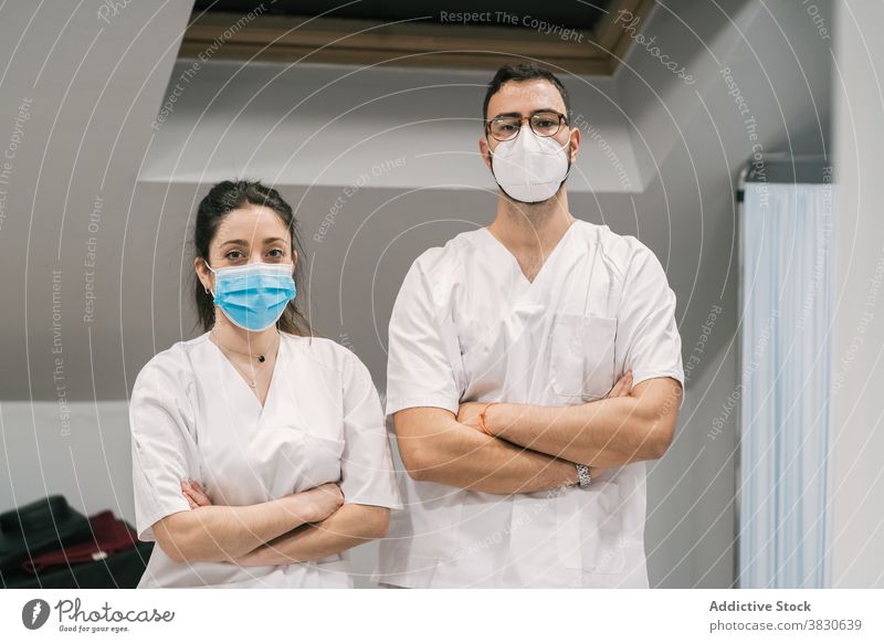 Lächelnde Ärzte in Uniform und Maske schauen in die Kamera Arzt Sanitäter Krankenhaus Personal heiter Beruf Spezialist professionell medizinisch stehen Dienst