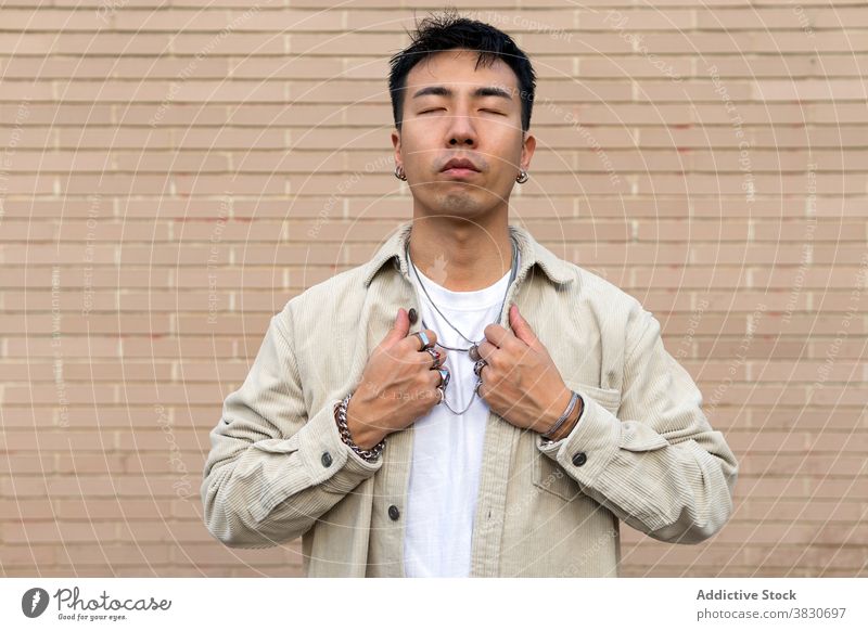 Nachdenklich asiatischen Mann stehend mit geschlossenen Augen gegen Backsteinmauer nachdenken Augen geschlossen Windstille emotionslos berühren Revers