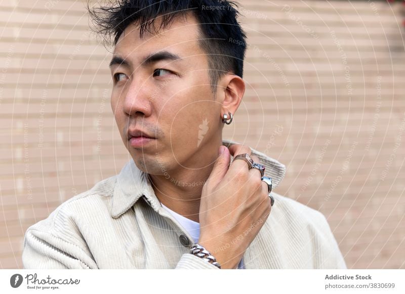 Nachdenklich asiatischen Mann stehend mit geschlossenen Augen gegen Backsteinmauer nachdenken Windstille emotionslos berühren Revers nachdenklich ernst