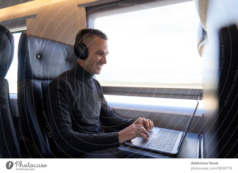 Mann mit Kopfhörern arbeitet an Laptop im Zug Business Ausflug Arbeit freiberuflich abgelegen Tippen reisen männlich Sitz modern Passagier Apparatur Gerät jung