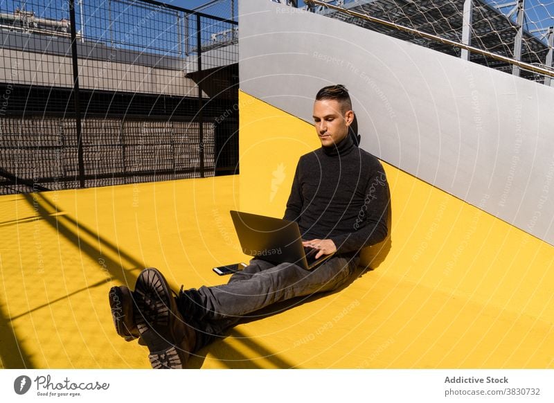 Junger Mann surft auf dem Laptop, während er draußen arbeitet Tippen Inbetriebnahme benutzend Fokus Konzentration ernst beschäftigt Browsen männlich online