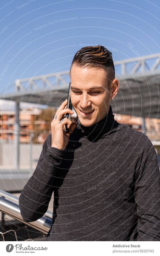 Junger Mann beim Telefonieren mit dem Smartphone benutzend Telefonanruf Kommunizieren Anruf Lächeln sprechen Arbeit positiv männlich diskutieren abgelegen