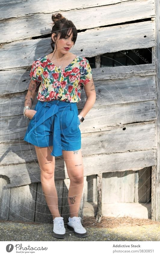 Nachdenkliche Frau neben der alten Holzkonstruktion nachdenklich Wand Stil Mode verträumt Außenseite hölzern besinnlich schlanke Shorts Hand-in-Tasche Hemd