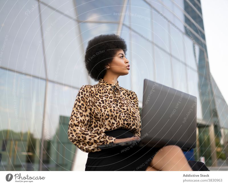 Serious schwarze Frau mit Laptop auf der Straße Mitarbeiter Konzentration Job Tippen Inbetriebnahme selbstbewusst ernst Browsen beschäftigt Arbeit benutzend