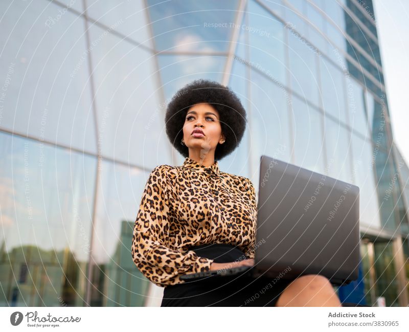 Serious schwarze Frau mit Laptop auf der Straße Mitarbeiter Konzentration Job Tippen Inbetriebnahme selbstbewusst ernst Browsen beschäftigt Arbeit benutzend