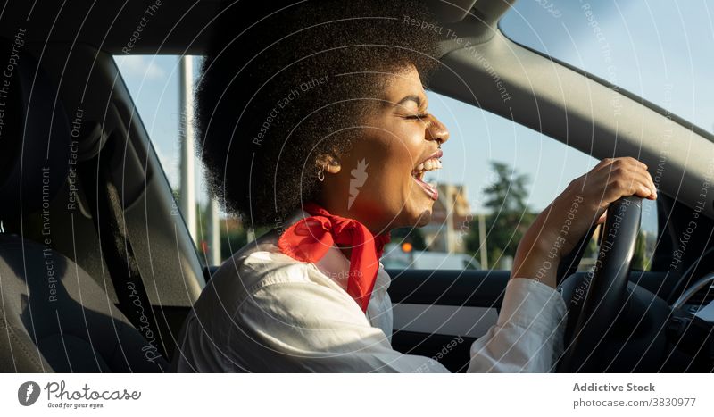 Glückliche schwarze Frau fährt Auto und lächelt hell aufgeregt Laufwerk PKW Augen geschlossen Lachen froh Freude Optimist heiter sich[Akk] entspannen Automobil