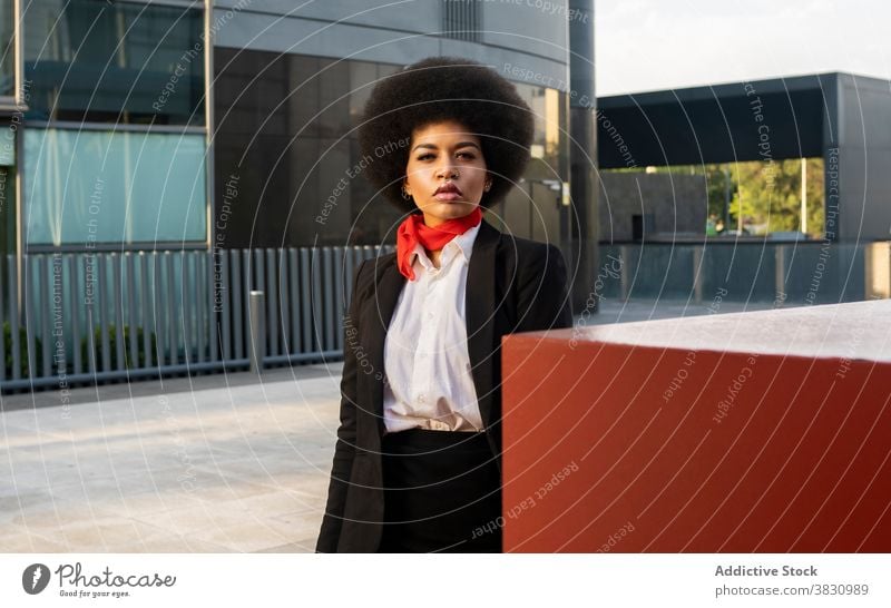 Selbstbewusste schwarze Frau in formalen Outfit steht in der Nähe von bunten Wand Konzentration Mitarbeiter elegant Beruf Arbeiter respektabel Stil