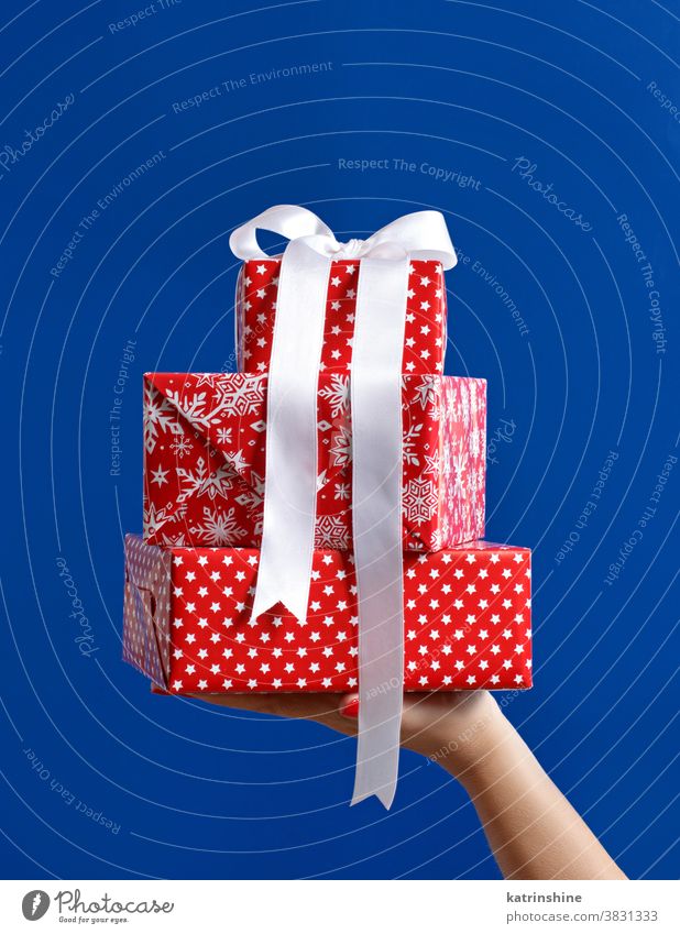 Rote Geschenkschachteln in der Hand haltend auf blauem Hintergrund Geschenkverpackung rot Weihnachten gesichtslos Schleife Bändchen vereinzelt abschließen Stern
