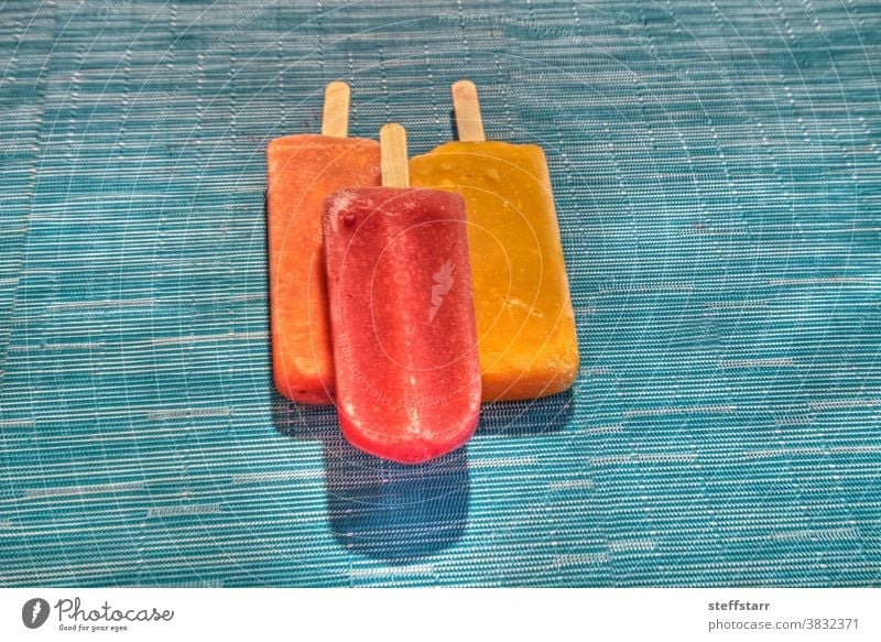 Eis am Stiel auf aquablauem Hintergrund im Sommer Stieleis Wassermelonen-Eis am Stiel Tropenfrüchte-Eis am Stiel Mango-Eis am Stiel Limetten-Eis am Stiel Frucht