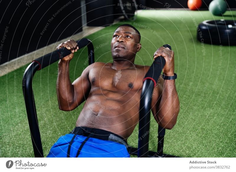 Schwarzer Mann macht Übungen am Parallelbarren parallel Bar Training Bizeps Pumpe nackter Torso Form Fitnessstudio männlich ethnisch schwarz Afroamerikaner