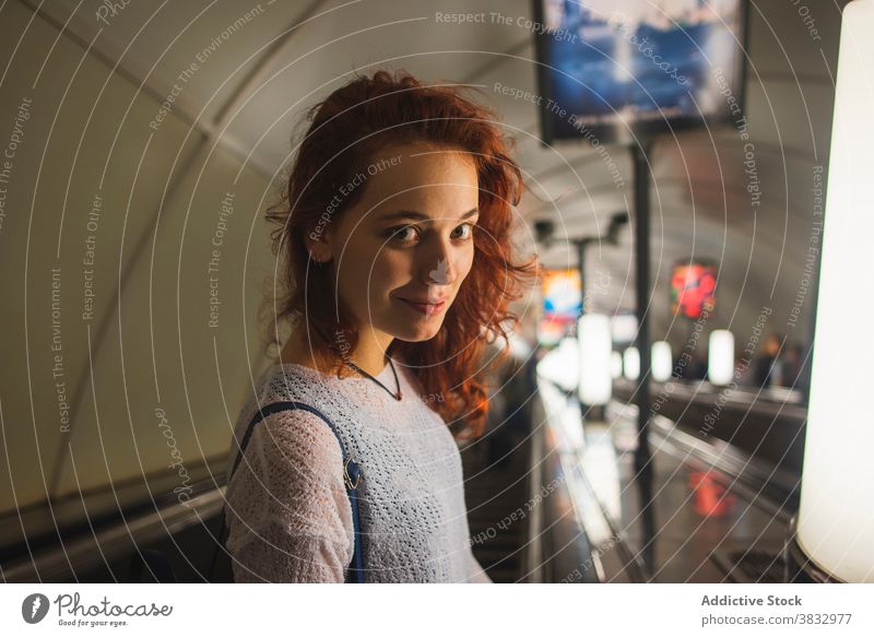 Lächelnde rothaarige Frau auf Rolltreppe stehend U-Bahn rote Haare Passagier Reisender positiv urban jung Rotschopf krause Haare Schüler Lifestyle reisen