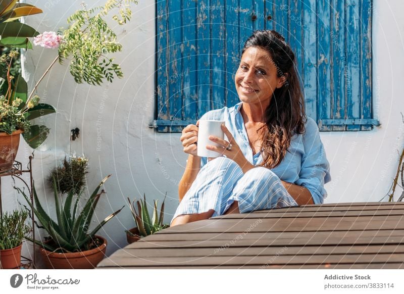 Lächelnde Frau trinkt Kaffee auf der Terrasse Glück heiter ruhen trinken Tasse Erwachsener ethnisch Getränk Optimist froh sich[Akk] entspannen Lifestyle Pause