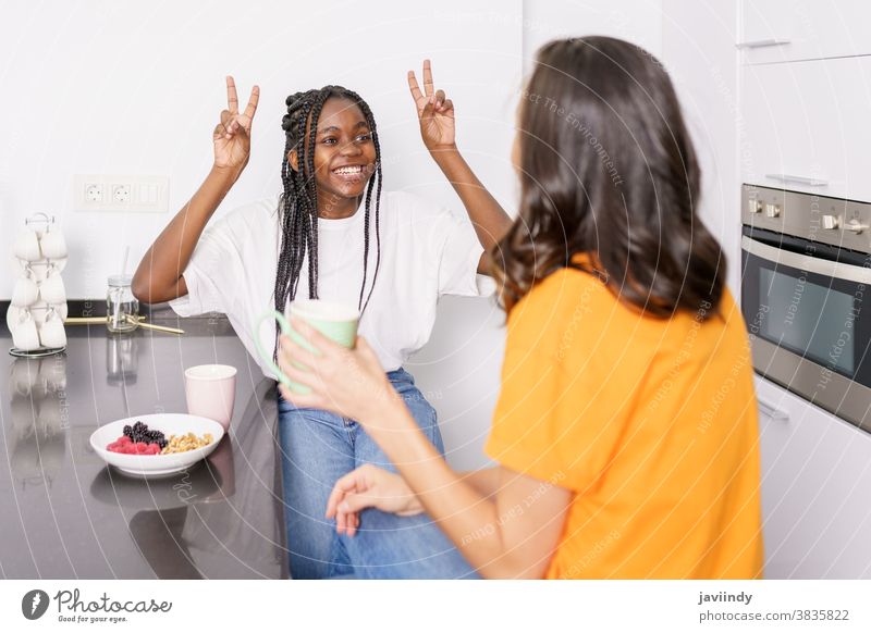 Zwei Freunde essen einen gesunden Snack, während sie sich zu Hause unterhalten Frauen Lebensmittel heimwärts Essen multiethnisch rassenübergreifend Gesundheit