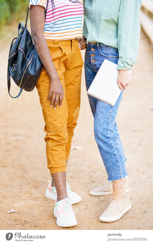 Zwei nicht erkennbare multiethnische Mädchen posieren zusammen mit farbenfroher Freizeitkleidung Frau Freund unkenntlich Tablette digital jung Lifestyle urban