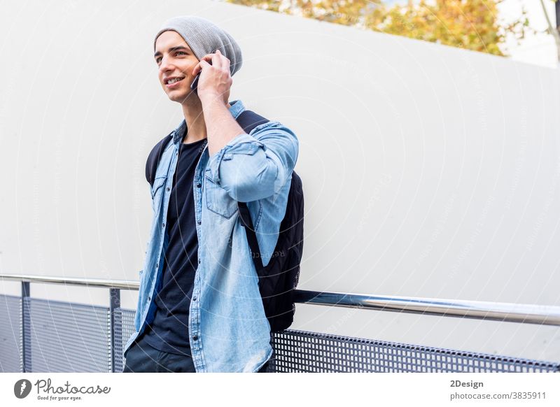 Städtischer stilvoller junger Mann, der mit seinem Handy an der Wand steht Stehen Telefon Smartphone sprechend Aufruf Typ Mobile männlich Technik & Technologie