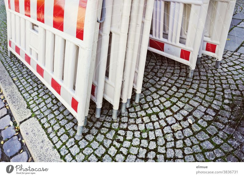 Mehrere rot-weiße Absperrbaken stehen aneinandergelehnt am Straßenrand Absperrtechnik Klappbaken Leitbake Fahrbahnteiler Sicherheit Sicherheitsbaken