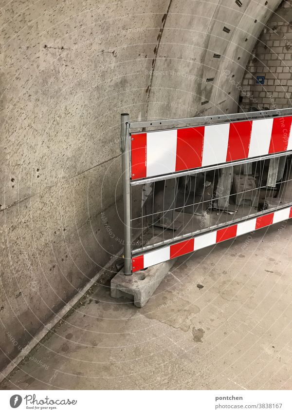 Ein rot-weiß gestreiftes Absperrgitter vor  einer Betonmauer.  Sicherheit, Warnung, Verbot Absperrung verbot durchgang unterirdisch Barriere Schutz Baustelle