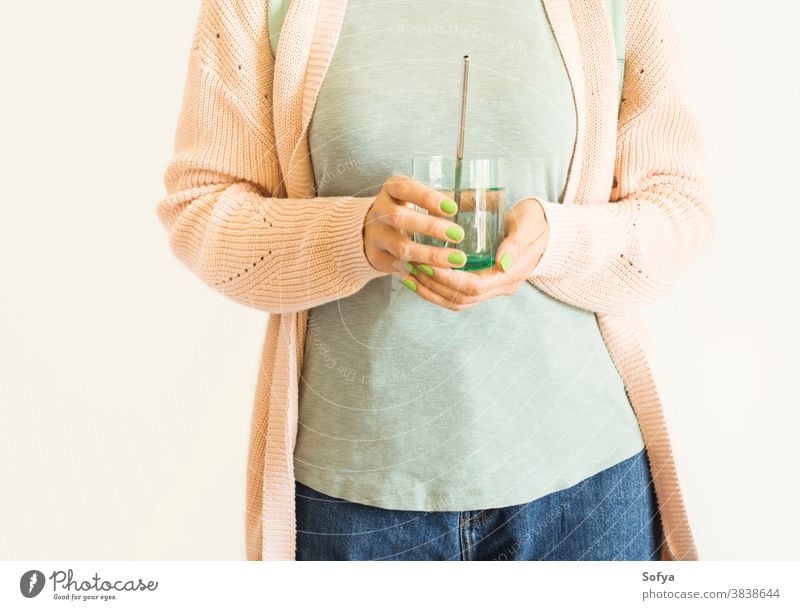 Frau hält ein Glas Wasser mit wiederverwendbarem Strohhalm keine Verschwendung Umwelt Öko trinken kunststofffrei rostfrei umweltfreundlich Pastell rosa Stahl