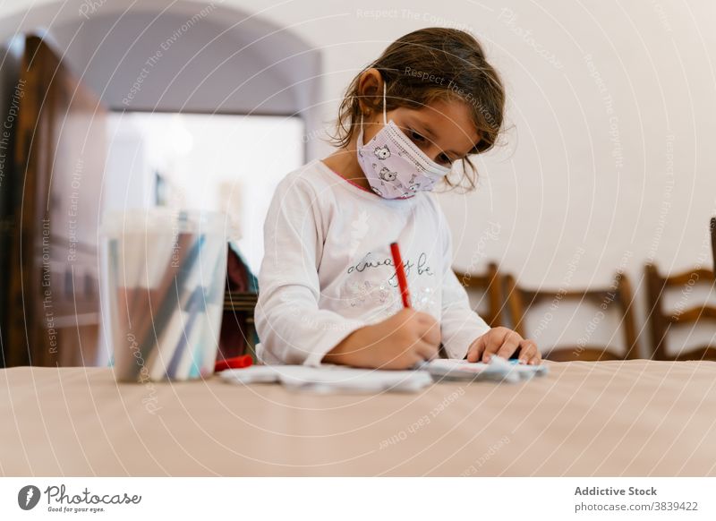 Nettes Mädchen Zeichnung auf dem Papier zu Hause zeichnen Kind Entwicklung Mundschutz Quarantäne Coronavirus klug lernen unterhalten heimwärts Tisch hölzern
