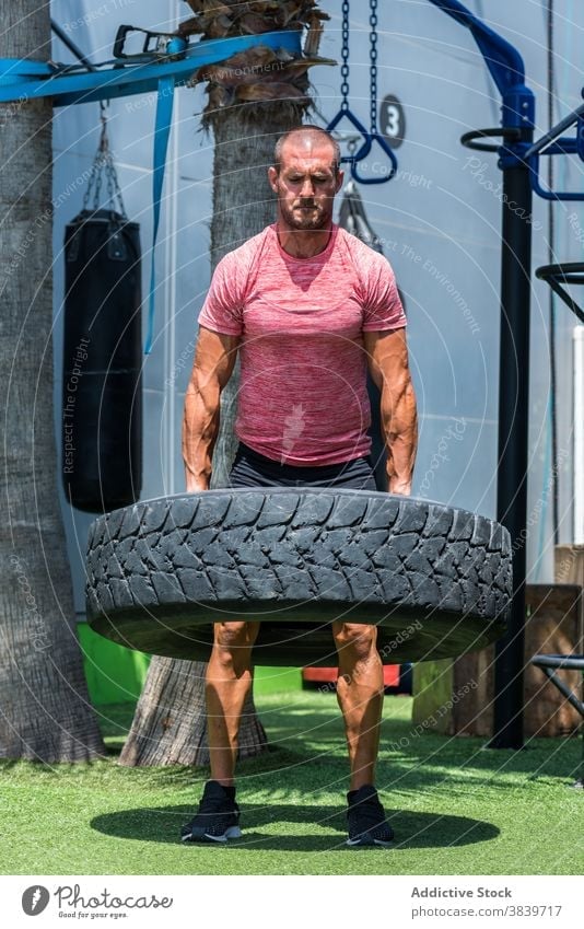 Starker Sportler bei Übungen mit schwerem Reifen Training Mann operativ stark heben Athlet männlich muskulös Kraft Gesundheit Energie Bestimmen Sie Fitness