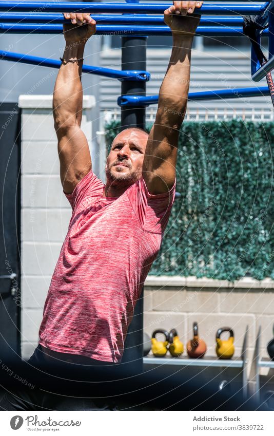 Mann, der während des Trainings auf einer Affenstange trainiert Übung Bar Sportler muskulös stark anstrengen Sportpark männlich Wellness Ausdauer passen