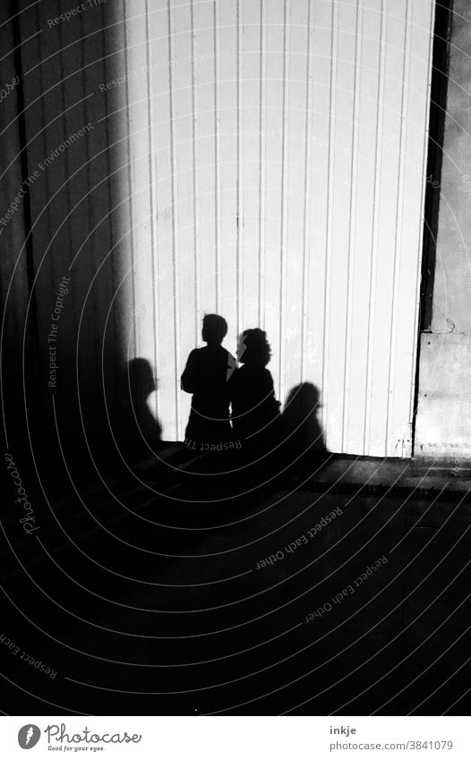 Schatten mehrerer Haushalte Schwarzweißfoto Licht Außenaufnahme Gruppe vier Personen Schlagschatten Fassade Wand trist Dunkel hell Kontrast Sonnenlicht