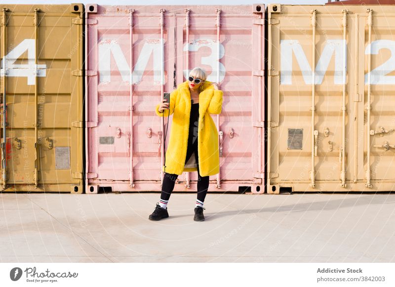 Frau in trendiger Kleidung nimmt Selfie in der Stadt tausendjährig trendy Outfit Smartphone Selbstportrait urban hell gelb Farbe Mantel Straße Großstadt jung