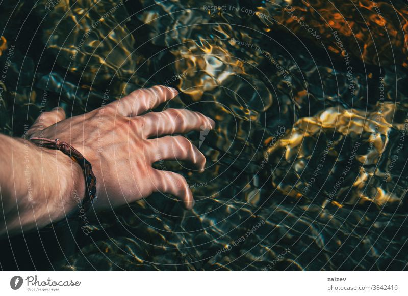 Nahaufnahme einer Hand, die die Wasseroberfläche mit Lichtreflexionen berührt menschlich Oberfläche Wasserreflexionen Wellungen Wellen unter Wasser berühren