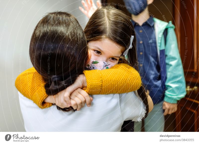 Mutter umarmt Tochter mit Maske, die von der Schule zurückkommt umarmend danach Schutzmaske covid-19 vorher Coronavirus Sohn Mädchen Sicherheit jung Kind